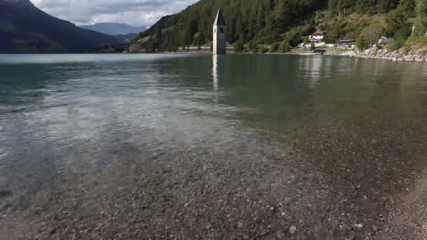 물에서 올라오는 커 콘 종탑이 있는 레시아 호수의 해변 — 비디오