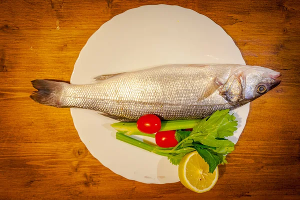 Robalo, limão, aipo e tomate sobre fundo de madeira — Fotografia de Stock