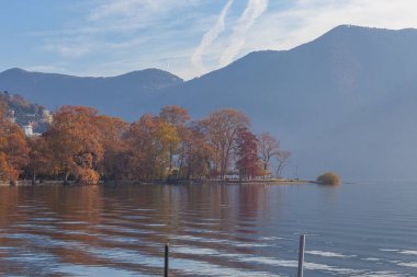 İsviçre 'nin Parco Ciani kentindeki Lugano Gölü kıyısında sonbahar renklerinde ağaçlardan oluşan bir panorama. Sükunet ve rahatlama kavramı