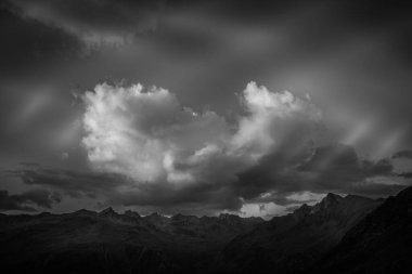 Dağların üzerinde güneşli bulutlar olan siyah ve beyaz alp manzarası, Vallelunga, Alto Adige Sudtirol, İtalya