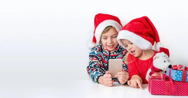 Онлайн рождественские поздравления. Брат и сестра в шляпах Санты улыбаются и разговаривают по телефону. — стоковое фото
