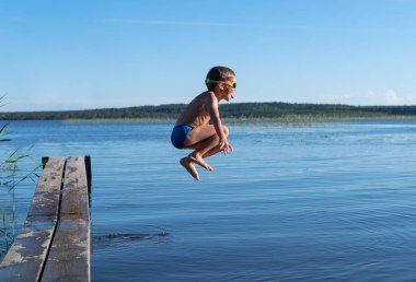 Oğlan yazın gün batımında göle atlar..