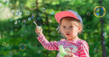 Dışarıda sabun köpüğüyle oynayan küçük bir kız. Yaz tatili.