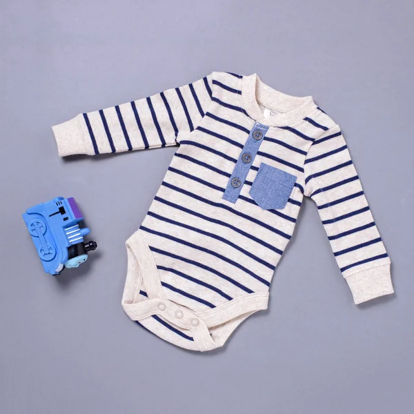 Baby onsie och leksak över Blå bakgrund — Stockfoto