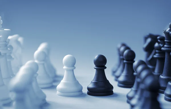 Confronting black and white chess pieces on a light blue background — Stock Photo, Image