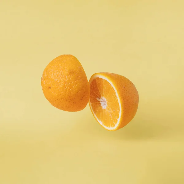 Food with vitamins tropical orange flying over pastel yellow background. Vegetarian organic food