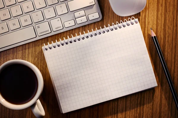 Cuaderno abierto con café junto a un teclado — Foto de Stock