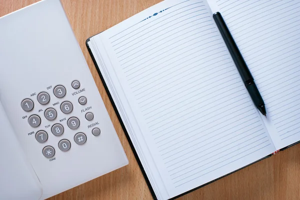 Ren anteckningsbok, penna och telefon på skrivbord — Stockfoto