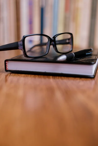 Lunettes de vue sur le dessus du livre à table Images De Stock Libres De Droits