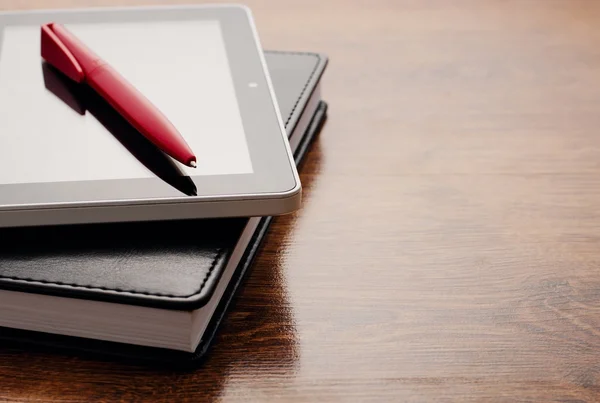 Dispositivo de tableta en el cuaderno en la mesa de madera — Foto de Stock