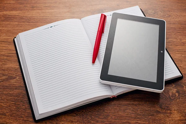 Caneta e Tablet em notas abertas na mesa de madeira — Fotografia de Stock