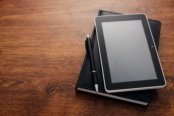 Pluma y tableta en la parte superior del libro cerrado en la mesa — Foto de Stock