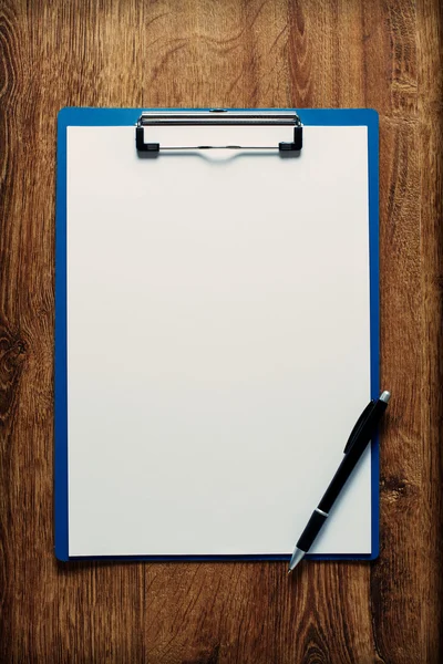 Blank clipboard and pen on a wooden desk — Stock Photo, Image