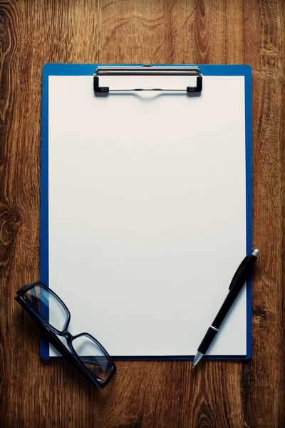 Eye-glasses and a black pen on an empty white page — Stock Photo, Image