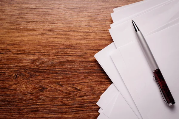 Weißes leeres Papier und Stift auf hölzerner Tischplatte — Stockfoto