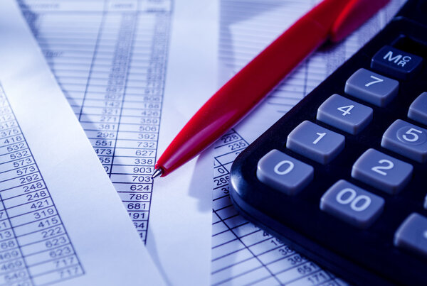 Калькулятор и ручка в верхней части бумажных отчетов
