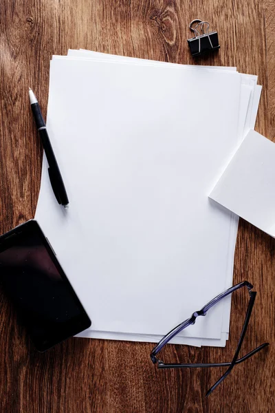 Bürobedarf mit Telefon und Brille auf dem Tisch — Stockfoto