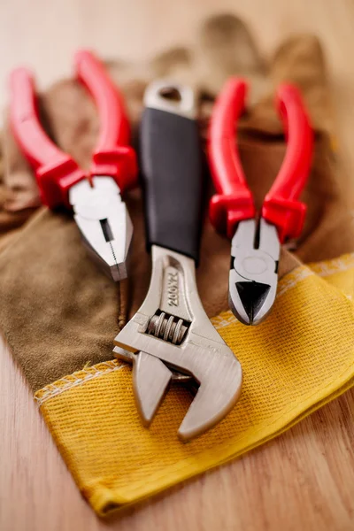 Verstellbarer Schraubenschlüssel, Zangen und Drahtschneider auf den Schutzhandschuhen — Stockfoto