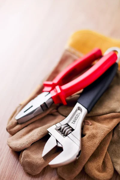 Adjustable wrench and pliers on top of the protective gloves — Stock Photo, Image