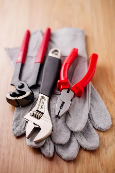 Verstellbarer Schraubenschlüssel, Zange und Nagelzug auf den Schutzhandschuhen — Stockfoto