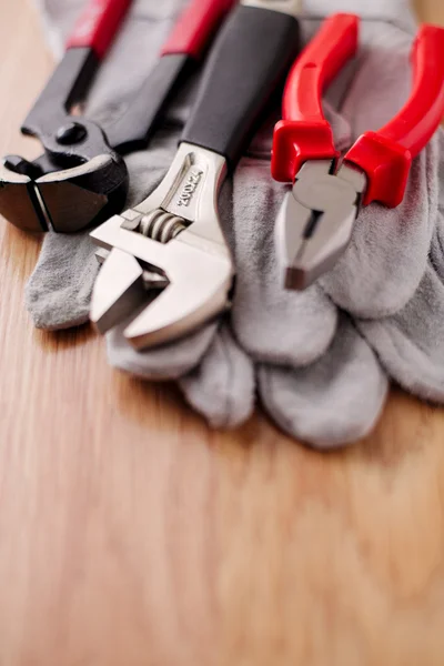 Adjustable wrench, pliers and nail puller on top of the protective gloves — Stock Photo, Image