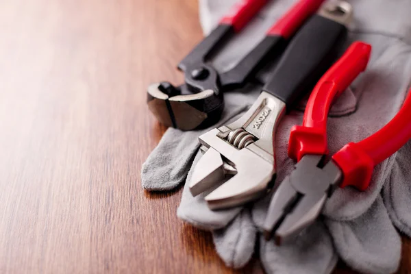 Verstellbarer Schraubenschlüssel, Zange und Nagelzug auf den Schutzhandschuhen — Stockfoto