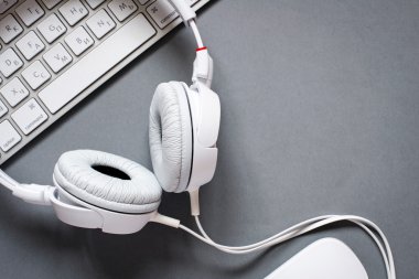 Beyaz kulaklık ve klavye gri masa üzerinde