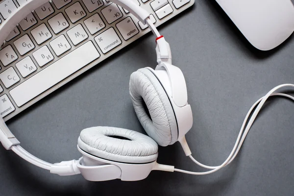 White Headphones and Keyboard on Grey Desk