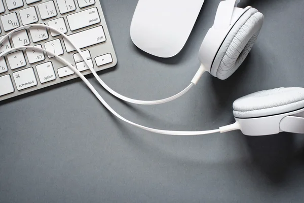 Λευκά ακουστικά, πληκτρολόγιο και το ποντίκι στο γραφείο του γκρι — Φωτογραφία Αρχείου