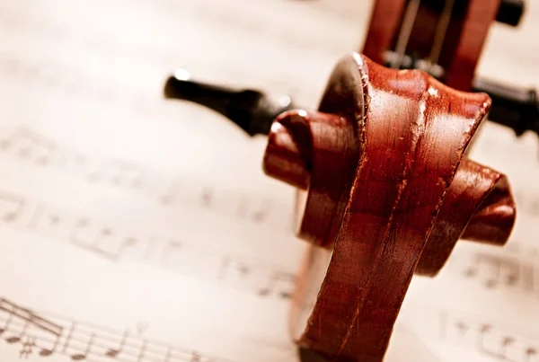 Rouleau de violon en bois sculpté reposant sur des partitions — Photo