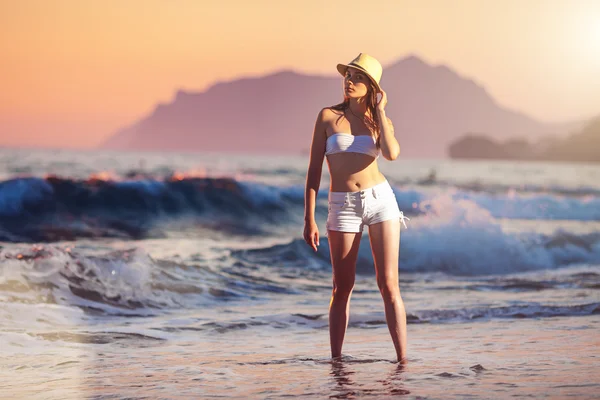 Kvinde på stranden ved solnedgang - Stock-foto