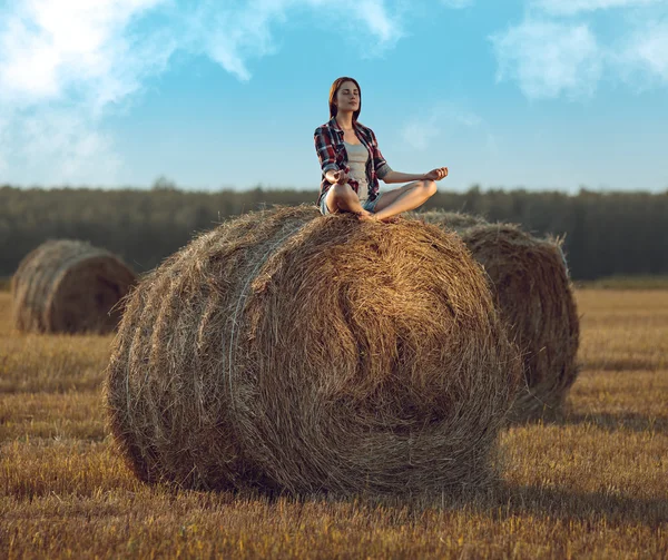 Young woman meditating on haystack — Stock Photo, Image