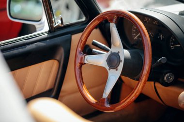 Eski bir arabanın içini detaylı bir şekilde görmek, ahşap ve metal direksiyonu ve yan aynayı gösteriyor..