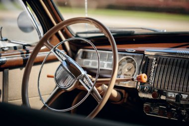 Eski arabanın iç kısmının yakın çekimi, direksiyonu, krom kontrolleri ve tahta gösterge panelini gösteriyor..