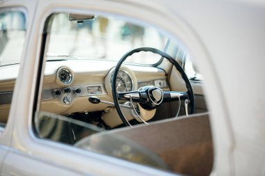 Gösterge paneli, krom ve klasik bir arabanın direksiyon simidi açık bir pencereden görülüyor..