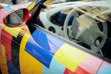 Dış yüzeyde cesur, renkli, soyut geometrik tasarımı olan modern bir spor arabanın yakın çekimi..