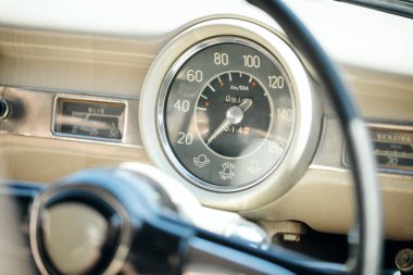Klasik bir arabanın iç mekanına yakın plan, İtalyan etiketli retro dairesel hız göstergesi ve göstergeleri.