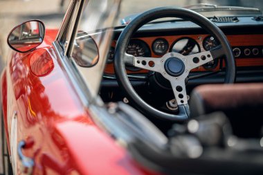 Kırmızı üstü açık spor bir arabanın içine bakın, direksiyonu, ahşap çerçeveli gösterge paneli, ve ayna.
