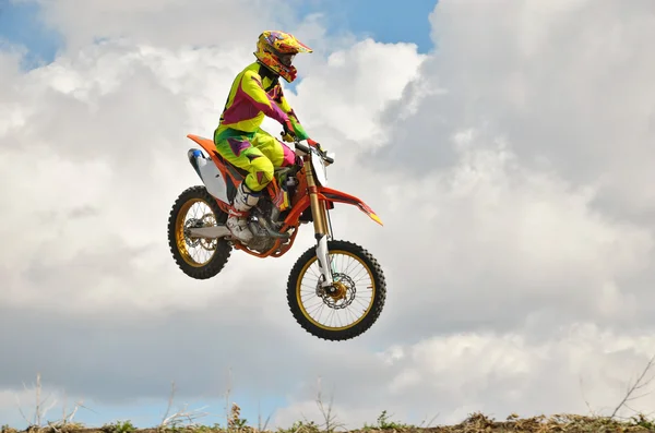 Motocross rider en una motocicleta aterriza espectacularmente en un borde de — Foto de Stock