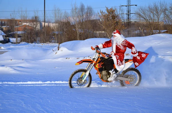 Санта-Клаус катается на велосипеде MX по глубокому снегу — стоковое фото