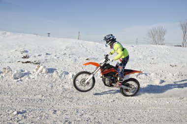Kış Motocross yarışçısı ayakta arka tekerlek üzerinde sürmek