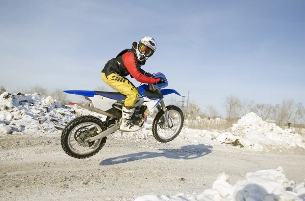 MX Winter rider soars from a hill looking back — стоковое фото