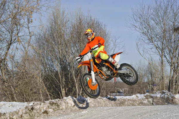 Rider on bike for MX flies over hill on snowy highway — Stock Photo, Image