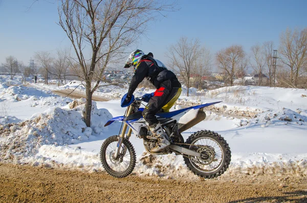 O motociclista em uma bicicleta voa no fundo das derivas de neve — Fotografia de Stock