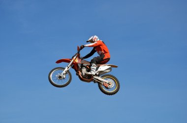 Freestyle sporcu açık mavi gökyüzü arka plan üzerinde bir motosiklet uçuş