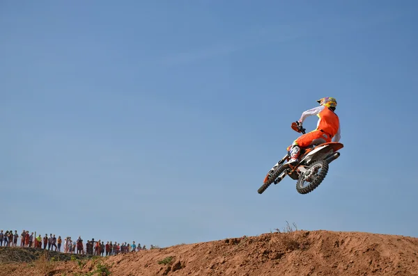 Motociclista volador en una motocicleta a través de una colina de tierra, disparado por la espalda — Foto de Stock