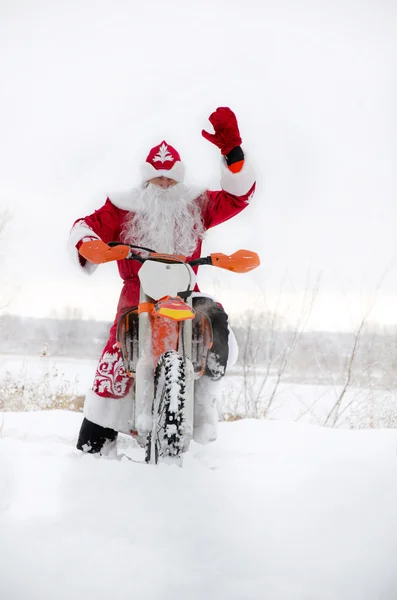 Papai Noel em uma motocicleta com a mão levantada motocross — Fotografia de Stock