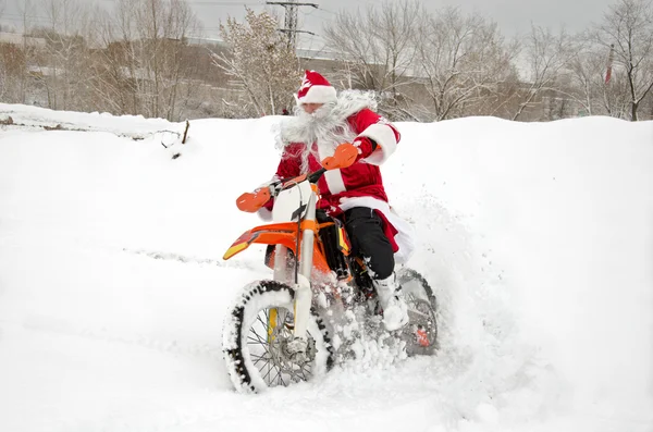 Arka tekerlek bir tüy ile kar snowdrifts ile Noel Baba bir motosiklet sürmek