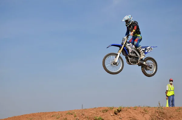 Op een motorfiets springt rider over een hoge heuvel van aarde — Stockfoto