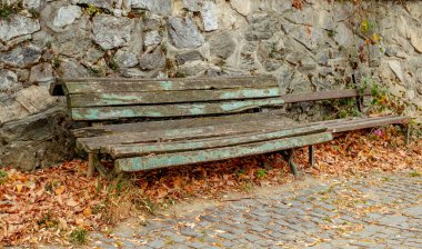 Kurumuş yapraklı eski ahşap bir bank.